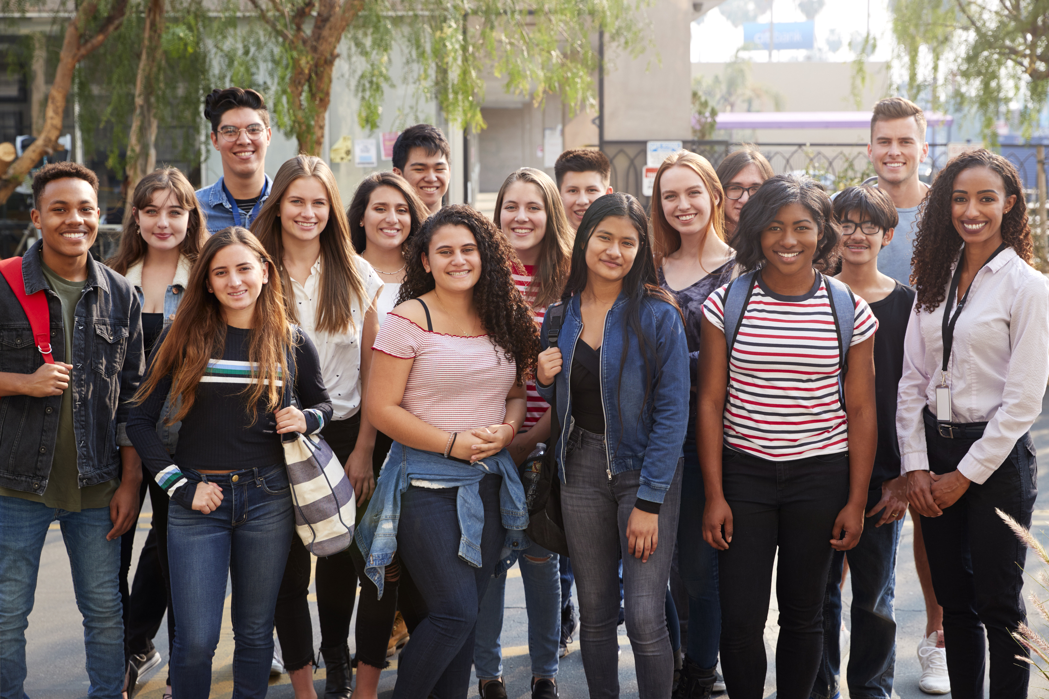 Portrait Of Smiling Male And Female College Students With Teachers Outside School Building